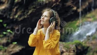 年轻时尚的美女，靠近瀑布听音乐的大监控耳机。